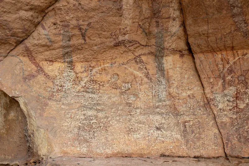 The left part of the panel, faded and crossed by cracks: tall dark figures, red curving lines and pale paint over the lower wall.